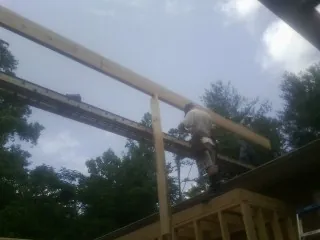 Carpenter setting a ridge beam over a new addition frame — Ice Dam Removal by Roofing Brothers in Great Neck