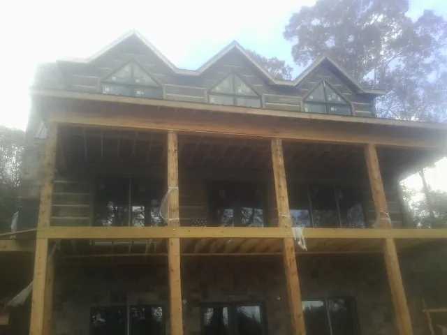 Dormers and porch framing on a large log home under construction — Roof Coating work by our crew in Great Neck