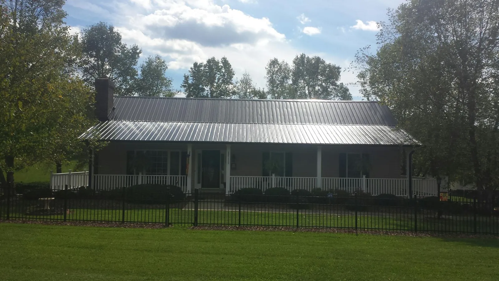 Gray metal roof on a brick ranch with a full width front porch — Gutter Guard Installation work by our crew in Great Neck